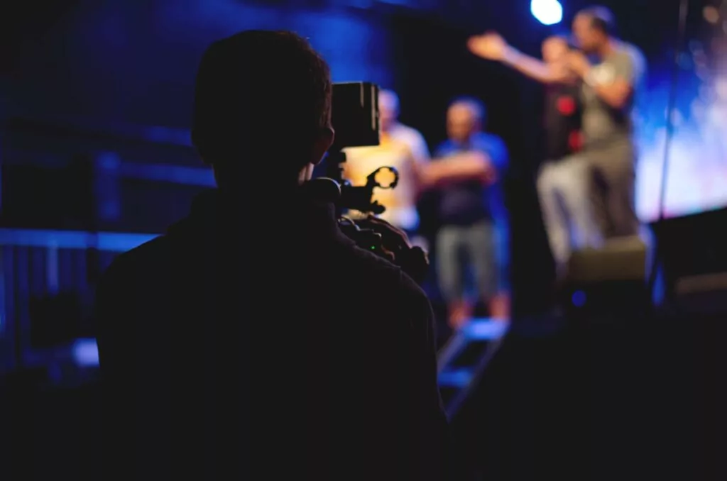 silhouette of camerman capturing video of speakers at an event